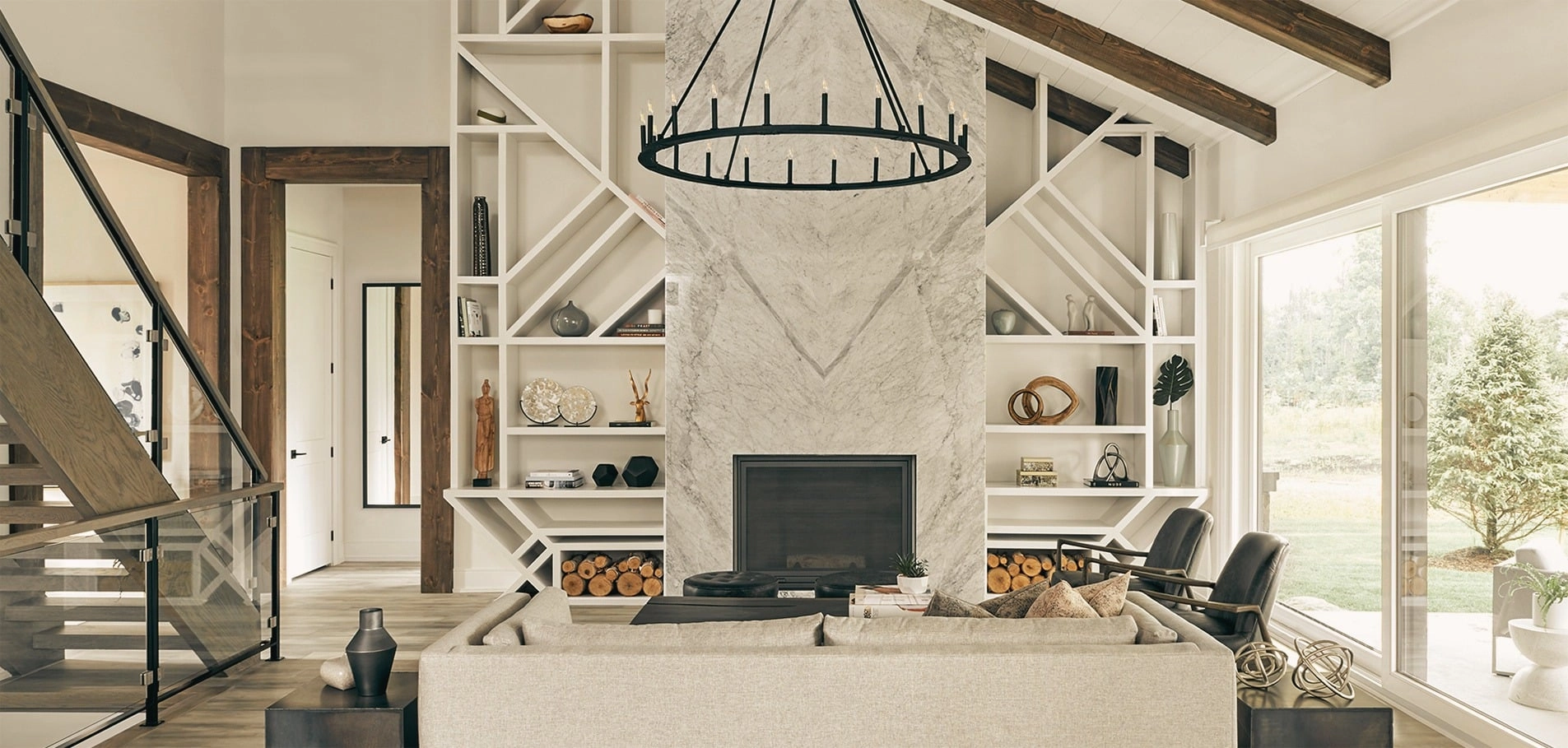 A living room with a marble fireplace, built-in shelving and a wrought-iron chandelier.