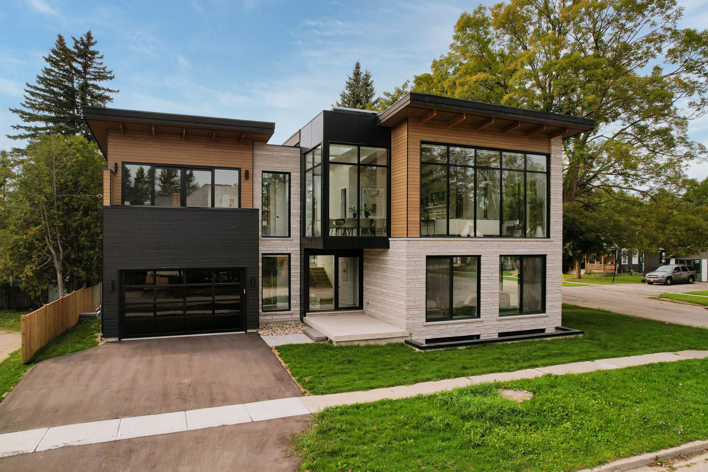 Front of 41 Alice Street viewed across the lawn, with stone walls, dark cladding and summer trees.