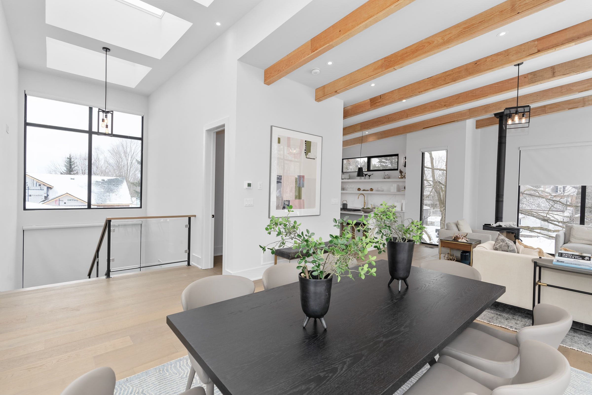Dining and living areas beneath a vaulted ceiling with exposed beams and a skylight.